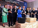 Uczestnicy-uroczystosci-stoja-na-scenie-z-kielniami-w-dloniach